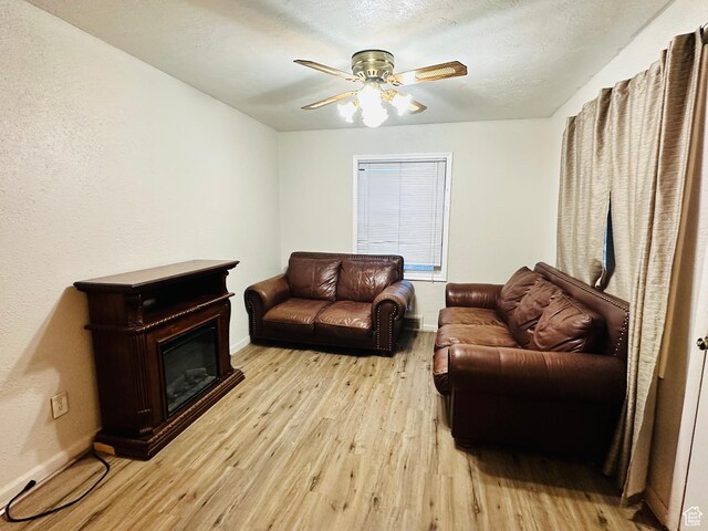living room with baseboards, light wood-type flooring, and a glass covered fireplace