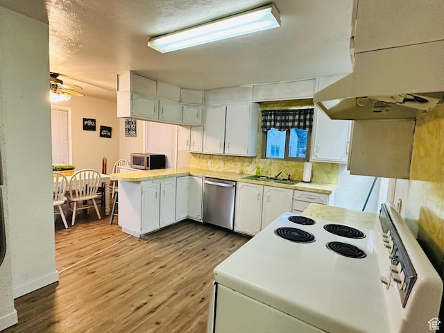 kitchen featuring white cabinetry, appliances with stainless steel finishes, under cabinet range hood, light wood finished floors, and a peninsula
