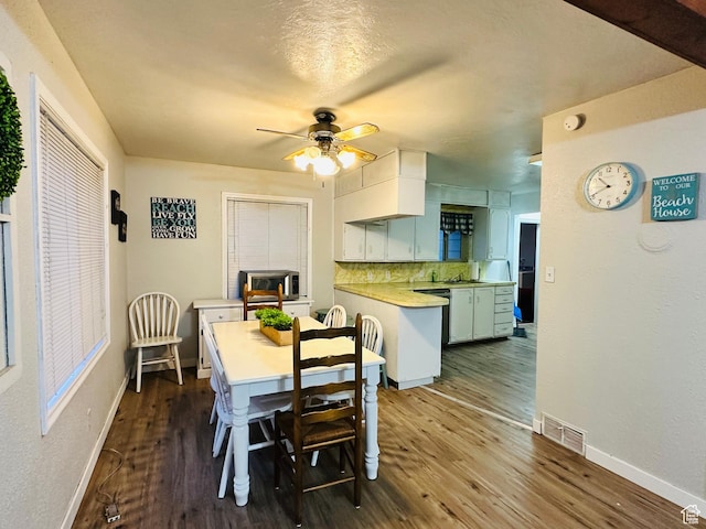 dining area with dark wood-style flooring, visible vents, a ceiling fan, and baseboards