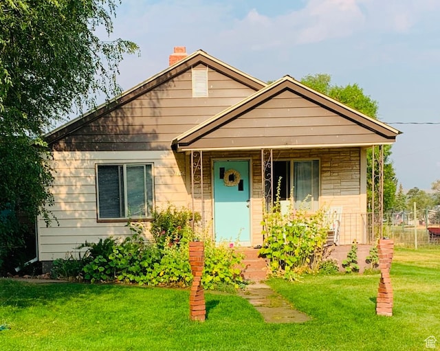 bungalow with a porch, a front yard, and a chimney