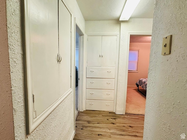 hallway with wood finished floors and a textured wall