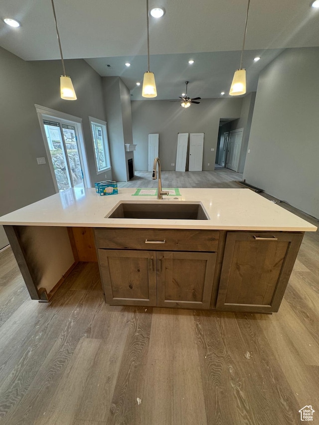1870 N Valley View Dr Unit 201, Layton, UT 84040 - kitchen featuring open floor plan, light wood-type flooring, light countertops, an island with sink, and decorative light fixtures