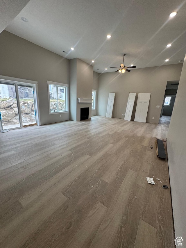 1870 N Valley View Dr Unit 201, Layton, UT 84040 - unfurnished living room with light wood-style flooring, a fireplace, recessed lighting, a ceiling fan, and a high ceiling