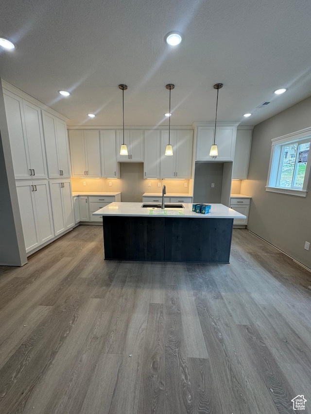 1870 N Valley View Dr Unit 201, Layton, UT 84040 - kitchen with wood finished floors, white cabinetry, light countertops, a center island with sink, and recessed lighting
