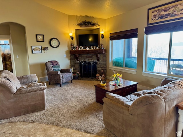 29 W Tamarind Way, Garden City, UT 84028 - tiled living area featuring a stone fireplace, visible vents, arched walkways, vaulted ceiling, and carpet flooring