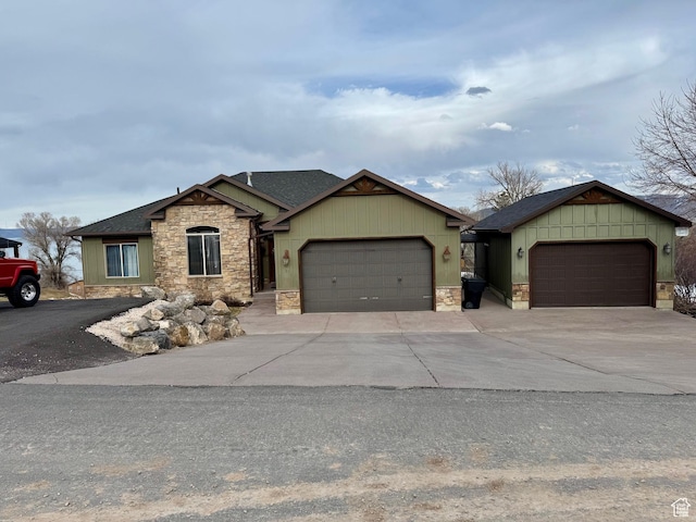 view of front facade with roof with shingles, an attached garage, stone siding, and concrete driveway
