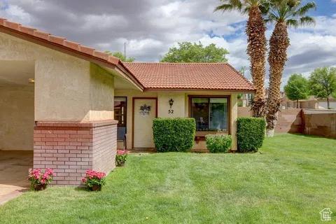 exterior space featuring a lawn, a tile roof, stucco siding, and brick siding