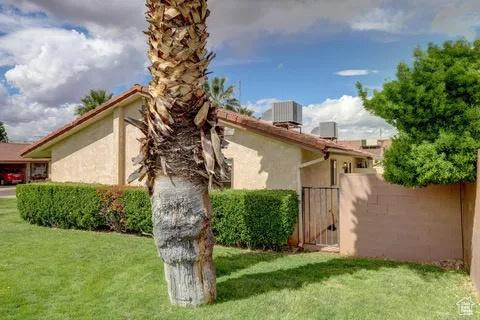 view of home's exterior featuring stucco siding, fence, a gate, central AC, and a lawn