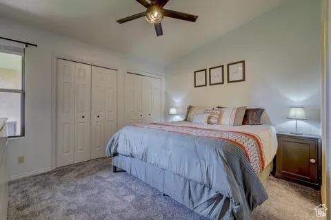 bedroom with lofted ceiling, a ceiling fan, carpet, and two closets