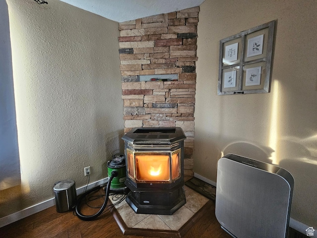 details with baseboards, wood finished floors, a wood stove, and a textured wall