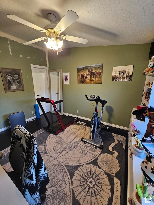 exercise room featuring a textured ceiling, baseboards, vaulted ceiling, and ceiling fan