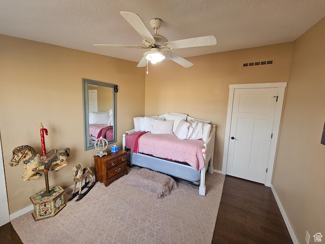 bedroom featuring baseboards, visible vents, a ceiling fan, and wood finished floors