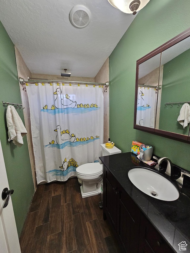 bathroom featuring a shower with curtain, vanity, wood finish floors, a textured ceiling, and visible vents