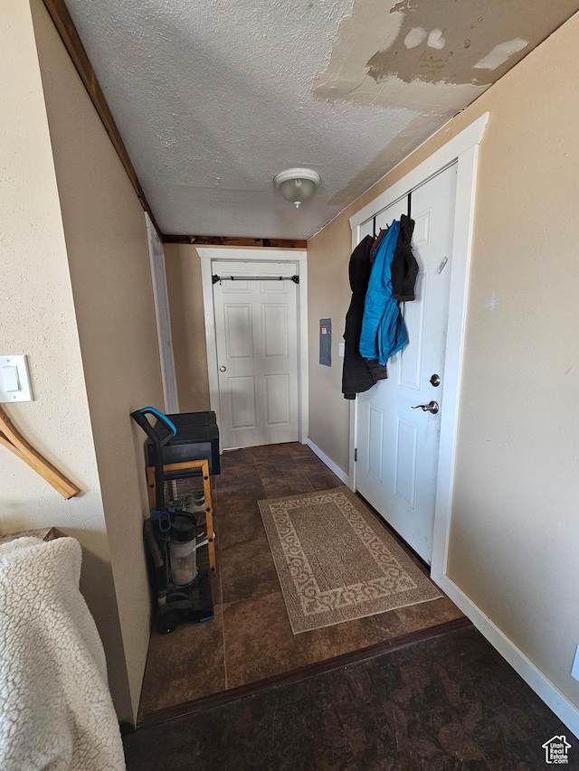 entryway featuring stone finish flooring, baseboards, and a textured ceiling