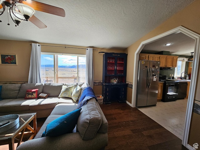 living area featuring light wood-type flooring, ceiling fan, and a textured ceiling