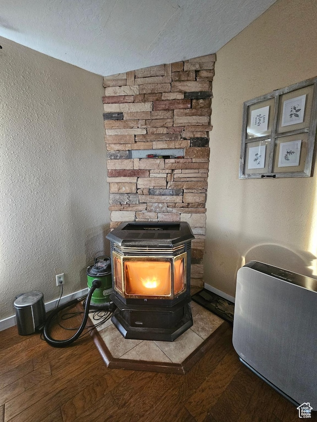 room details featuring baseboards, wood finished floors, a wood stove, and a textured ceiling