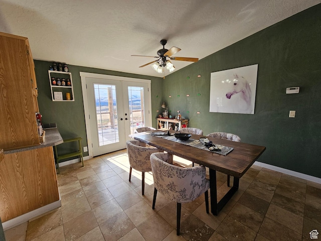 dining area with baseboards, ceiling fan, french doors, and a textured ceiling