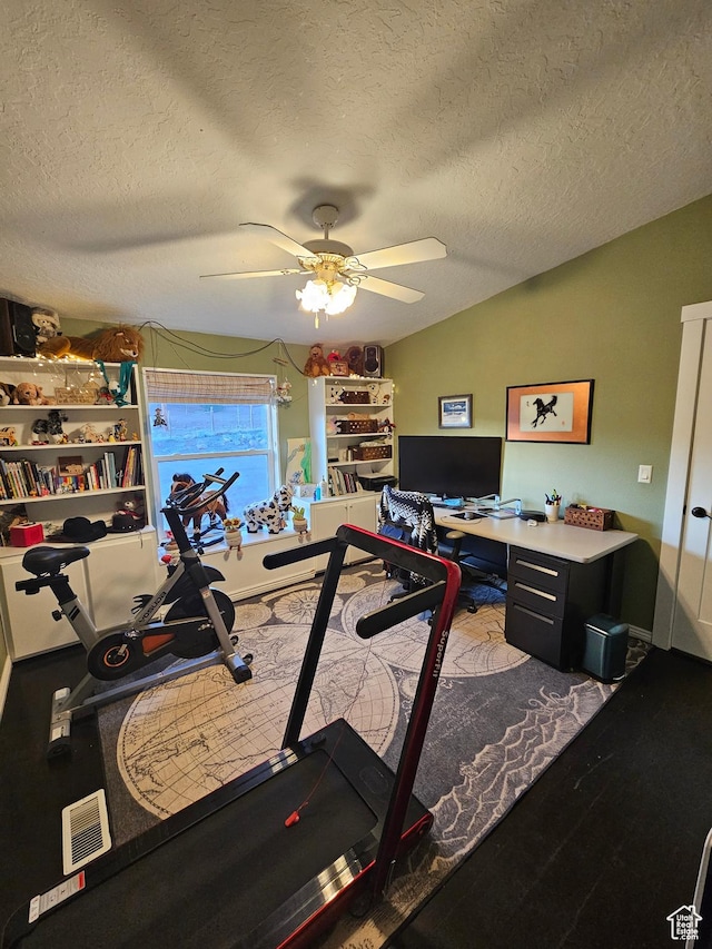 exercise area featuring lofted ceiling, ceiling fan, and a textured ceiling