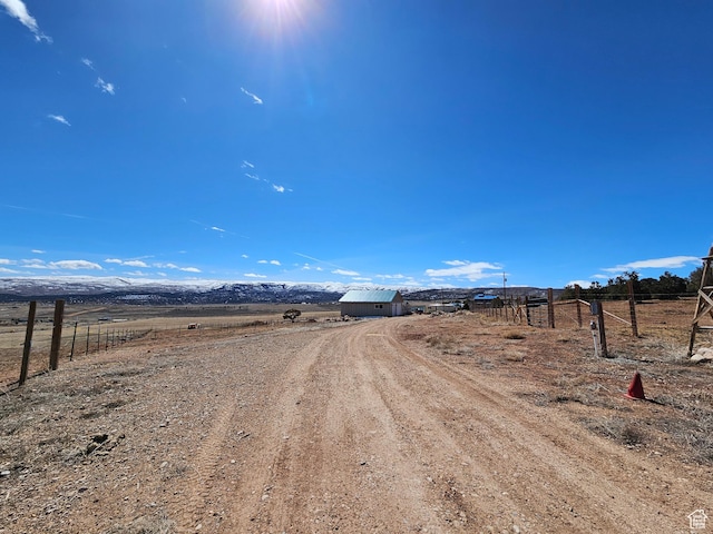 view of road with dirt driveway and a rural view