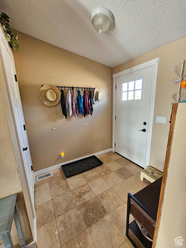 entryway featuring a textured ceiling, baseboards, and visible vents