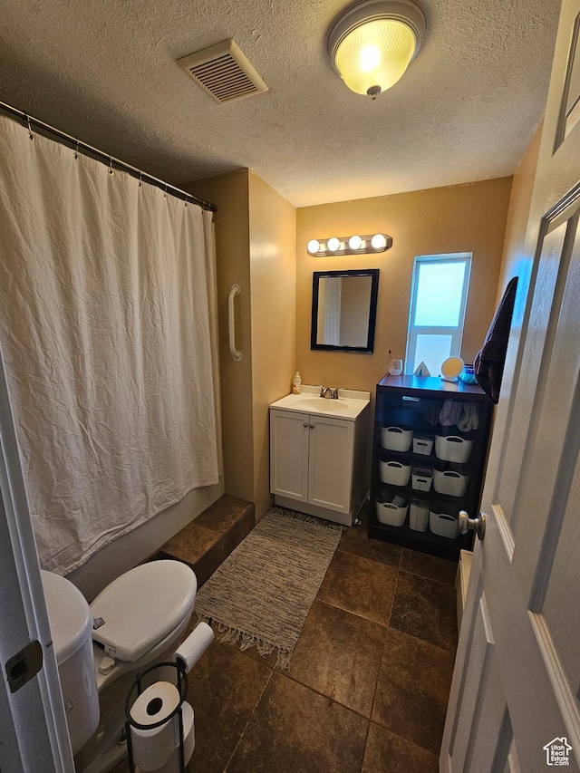 bathroom featuring a shower with curtain, vanity, toilet, a textured ceiling, and visible vents