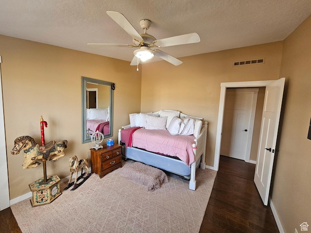 bedroom with baseboards, visible vents, wood finished floors, and a textured ceiling