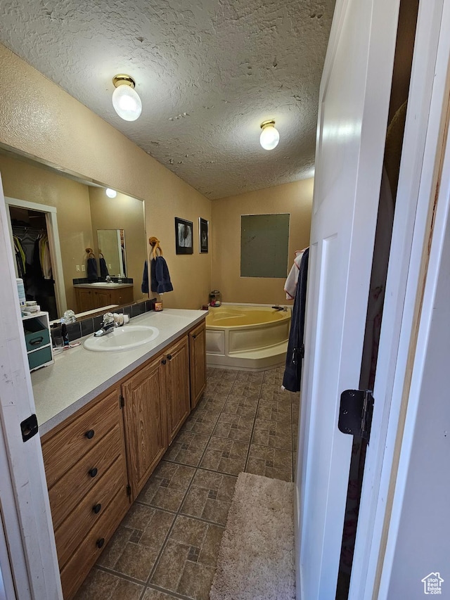 full bathroom featuring vanity, a garden tub, and a textured ceiling