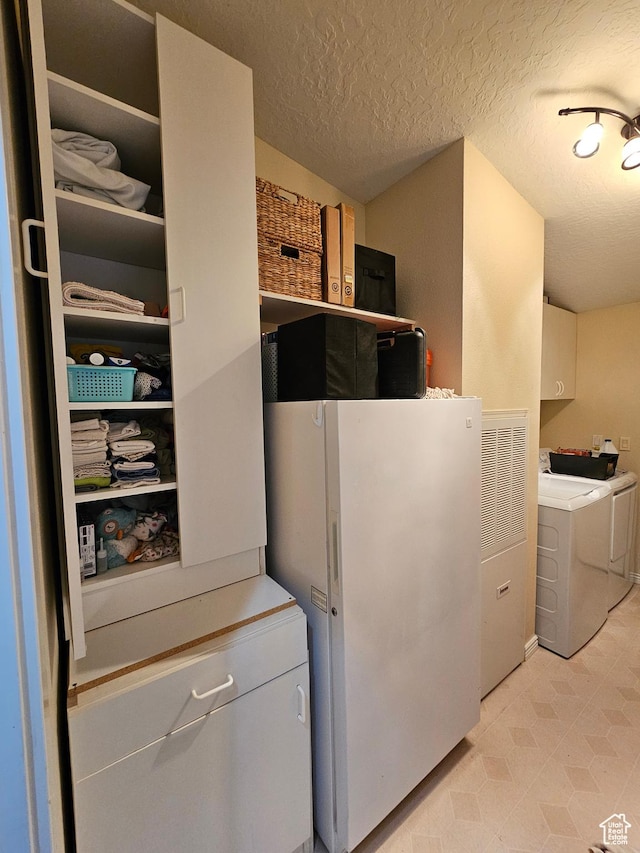 clothes washing area featuring light floors, cabinet space, separate washer and dryer, and a textured ceiling