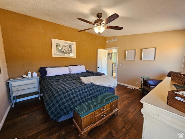 bedroom featuring a textured ceiling, baseboards, and dark wood finished floors