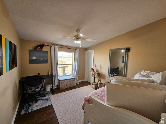 bedroom featuring lofted ceiling, dark wood-style flooring, baseboards, a textured ceiling, and ceiling fan