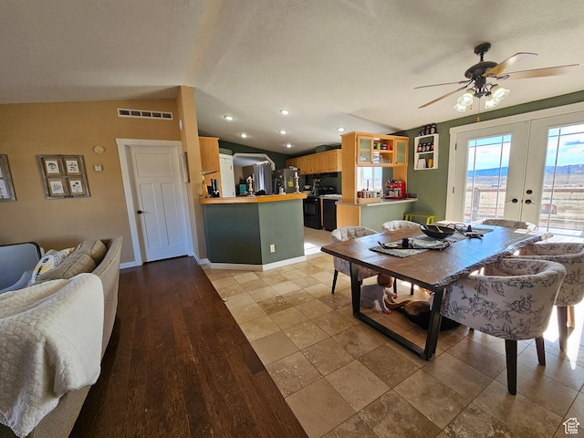 dining area featuring vaulted ceiling, french doors, a textured ceiling, visible vents, and a ceiling fan
