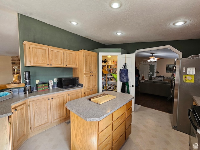 kitchen with light brown cabinets, freestanding refrigerator, and light floors