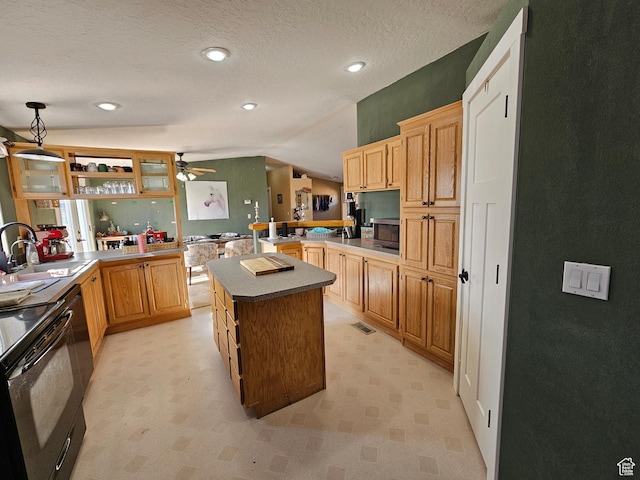 kitchen featuring a peninsula, ceiling fan, stainless steel microwave, lofted ceiling, and a sink