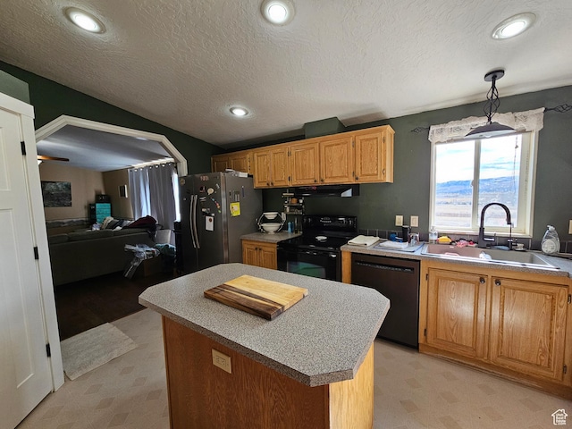 kitchen featuring a center island, black appliances, light floors, and a sink