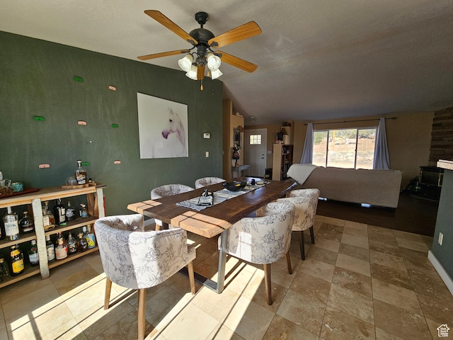 dining room featuring a ceiling fan, baseboards, and lofted ceiling