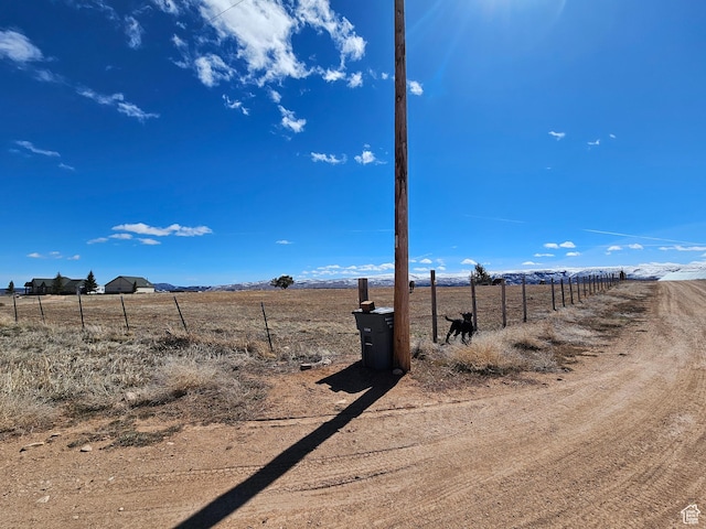 view of yard with fence and a rural view