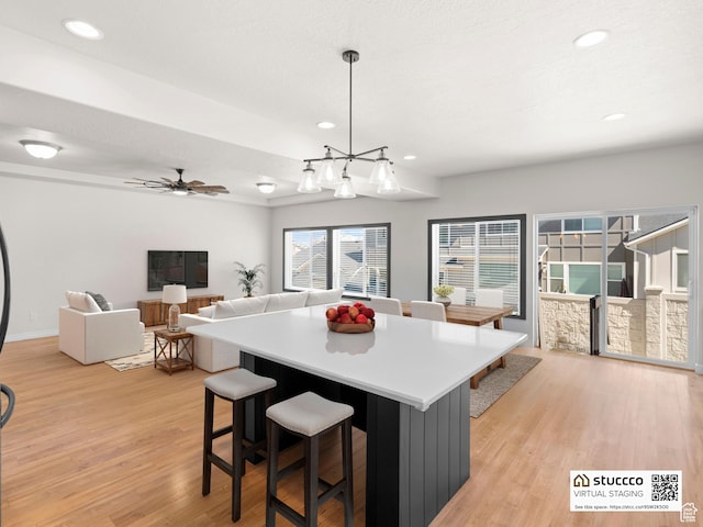 14353 S Ashvale Dr, Herriman, UT 84096 - kitchen with light wood finished floors, a kitchen bar, recessed lighting, a kitchen island, and light countertops