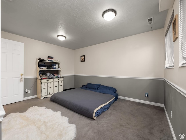 carpeted bedroom with baseboards, a textured ceiling, and visible vents