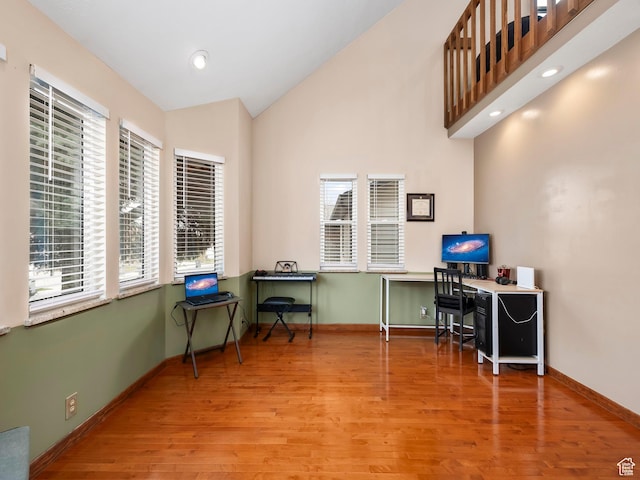 home office with baseboards, high vaulted ceiling, and wood finished floors