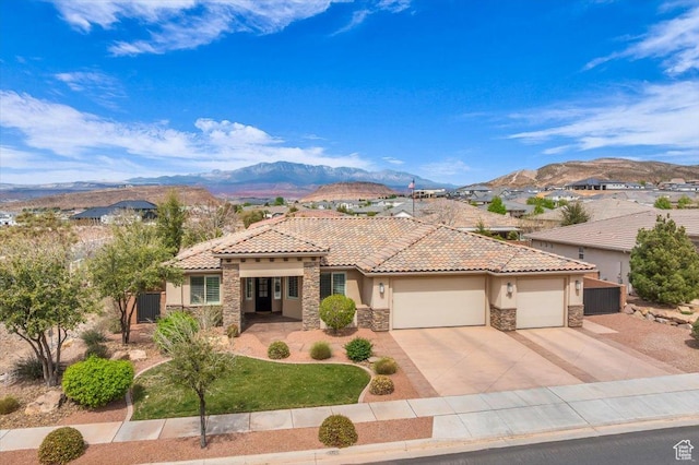 mediterranean / spanish-style home with stucco siding, an attached garage, stone siding, a tiled roof, and a mountain view