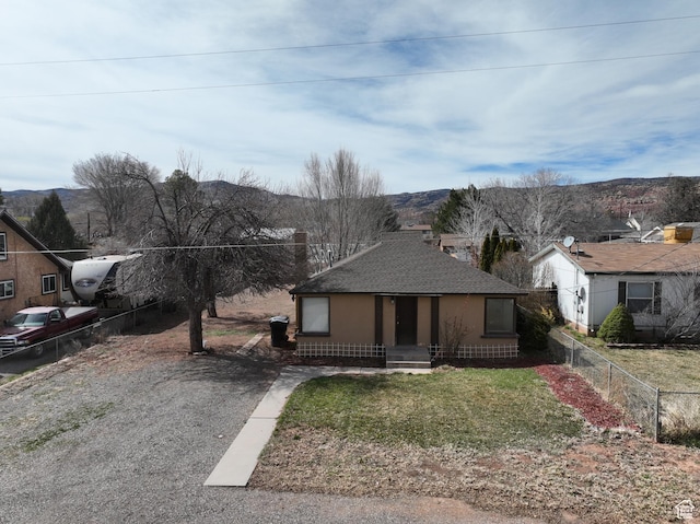bungalow-style house with a front yard, fence, and roof with shingles