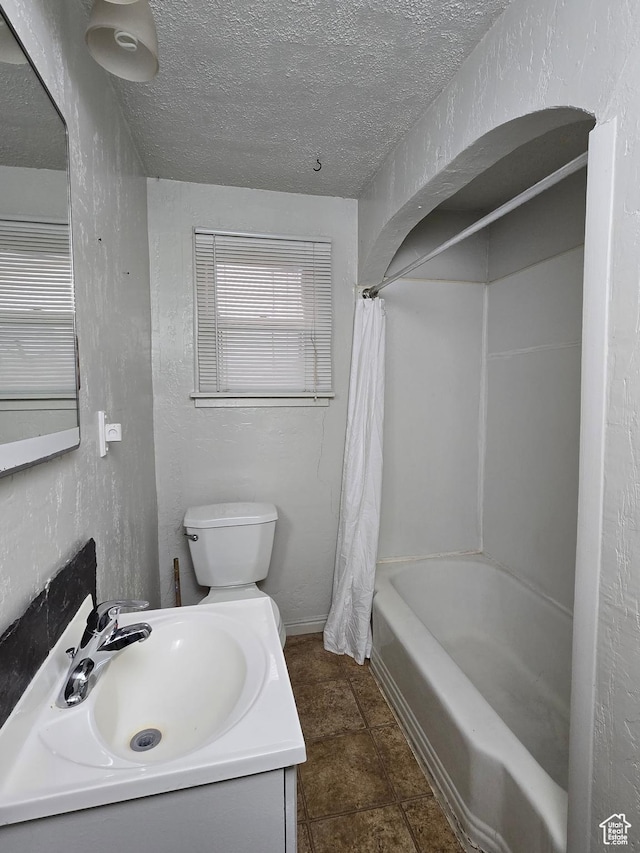 full bath featuring a textured ceiling, a textured wall, and toilet
