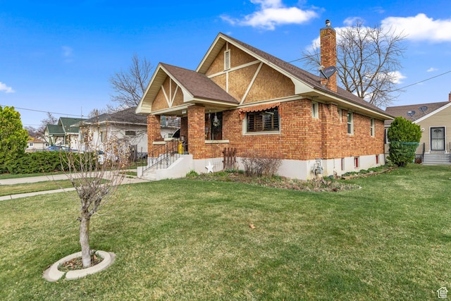english style home with roof with shingles, a chimney, a front lawn, and brick siding
