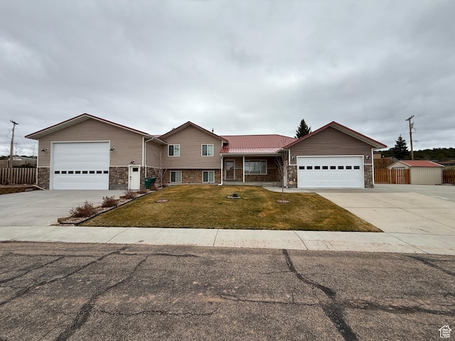 tri-level home featuring stone siding, fence, an attached garage, concrete driveway, and a front lawn
