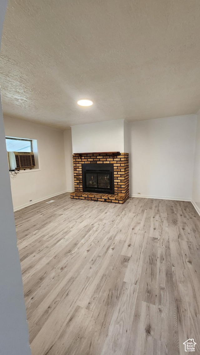 84 N 550 E, Spring City, UT 84662 - unfurnished living room with cooling unit, baseboards, a textured ceiling, a glass covered fireplace, and wood finished floors