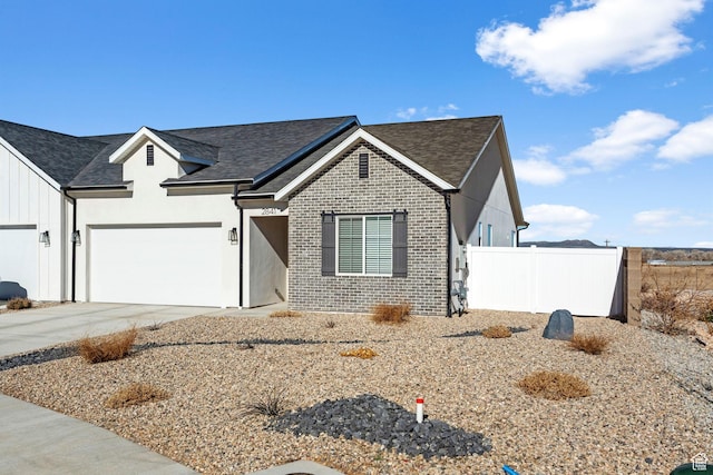 view of front of property with driveway, roof with shingles, fence, brick siding, and a garage
