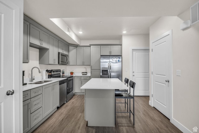 kitchen with gray cabinets, a kitchen bar, a sink, and stainless steel appliances