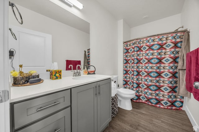 full bath with toilet, a shower with shower curtain, wood finished floors, and vanity