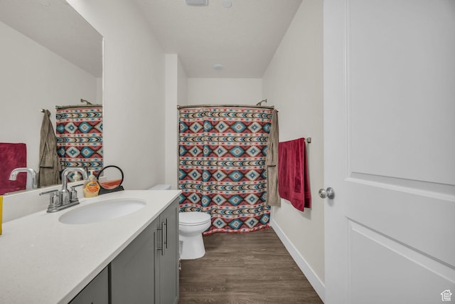 bathroom with a shower with curtain, vanity, toilet, baseboards, and wood finished floors
