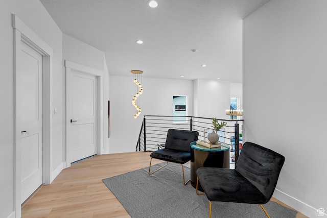 living area with baseboards, light wood-type flooring, an upstairs landing, and recessed lighting